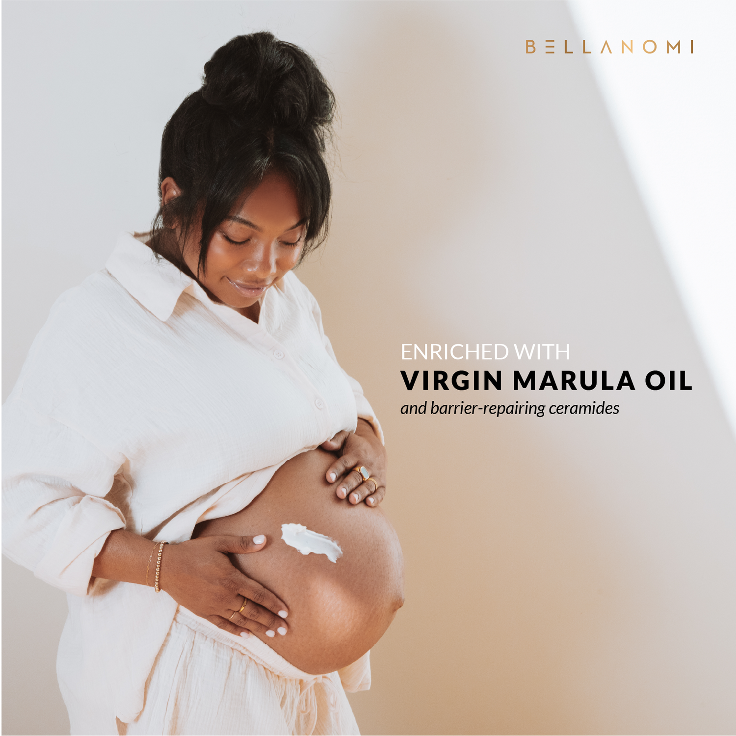 Woman holding her pregnant belly with a Bellanomi body cream applied on her skin